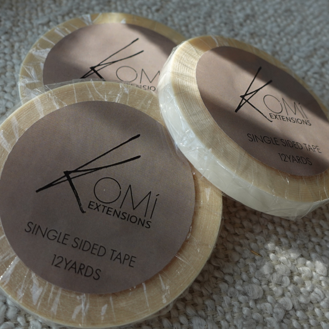Flat lay of Komi Extensions Single-Sided Replacement Tape rolls with branded labels for hair extensions.