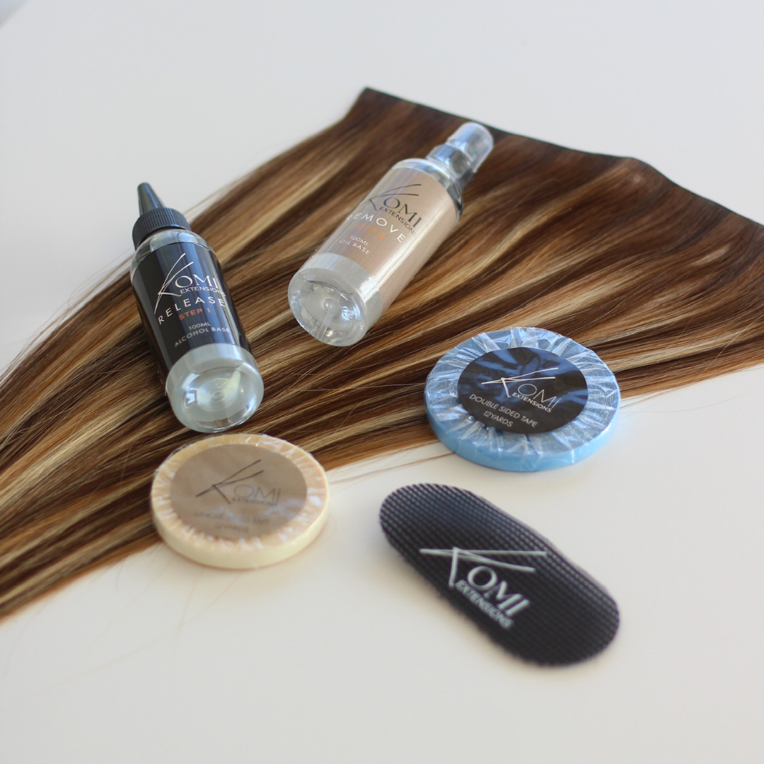 Flat lay of Komi Extensions Tape Weft Tool Kit showing sprays, tapes, color swatches, and comb on extension hair strands