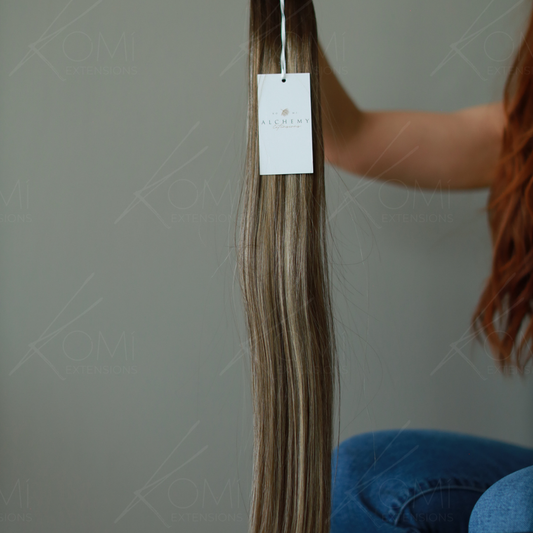 Long, highlighted hair extensions held upright to show their length and color blend