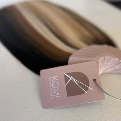Komi Extensions Color Ring swatches hanging with branded tag, showing natural and blended hair shades