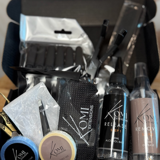 Open Komi Extensions Tape Weft Kit box with tape wefts, release sprays, tools, and accessories for professional installation