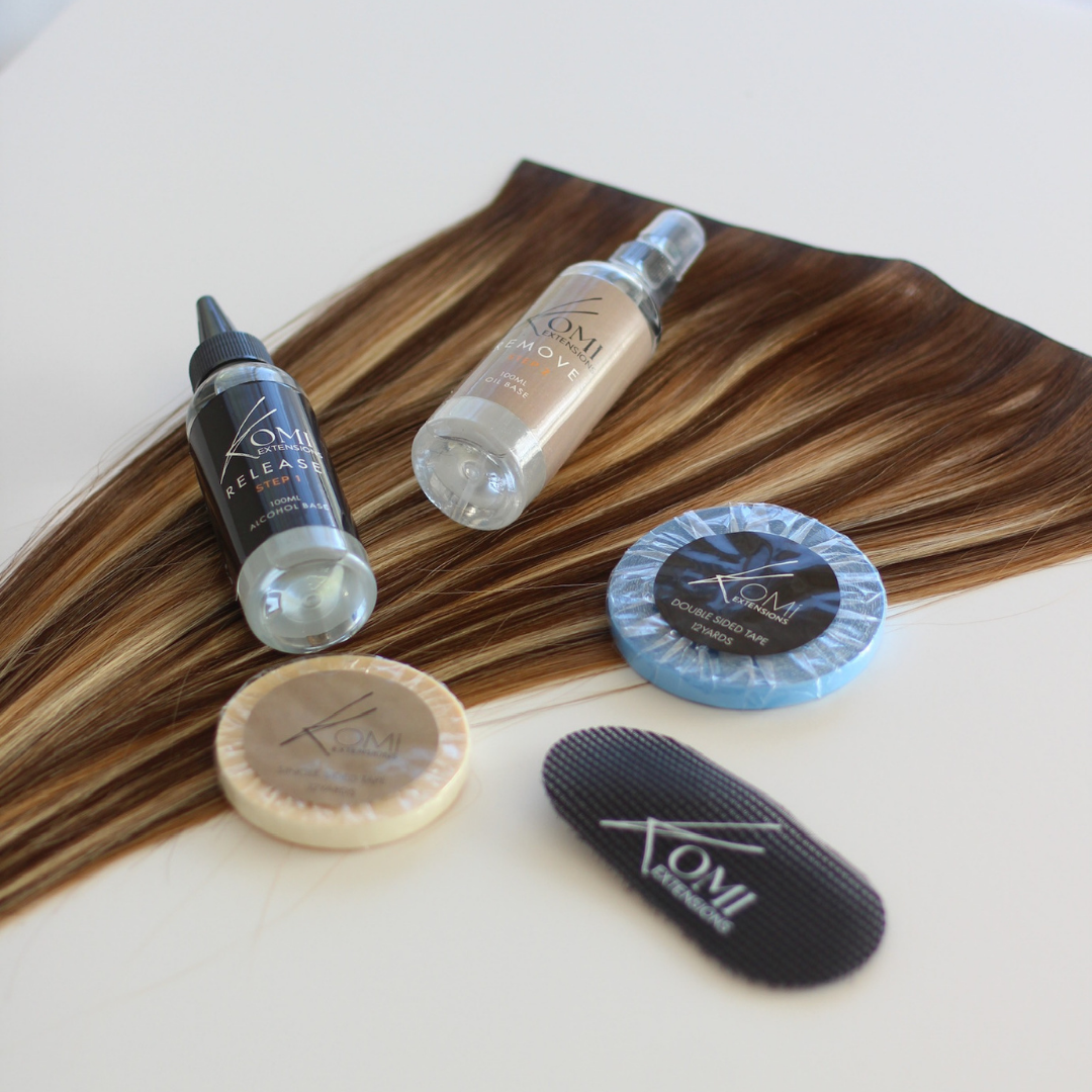 Flat lay of Komi Extensions Tape Weft Kit with extension hair strands, tapes, remover sprays, and styling tools.